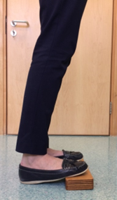 standing with toes on a board to stretch calf